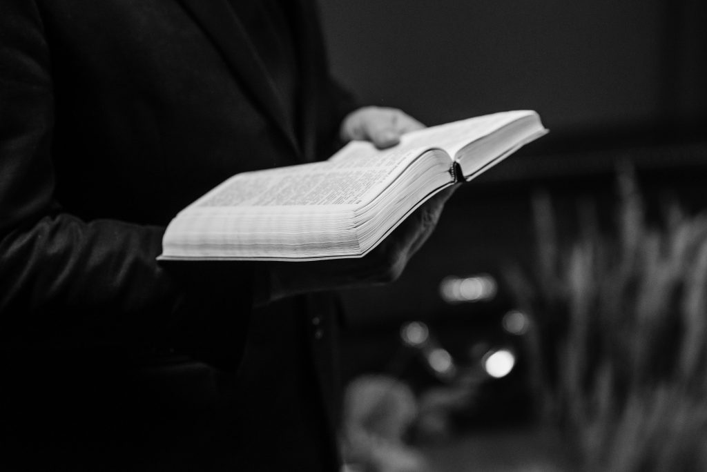 Grayscale close-up of a person holding an open Bible, conveying a sense of faith.